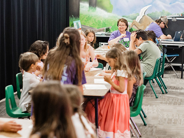 DC Kids volunteer and a kids sitting at a table