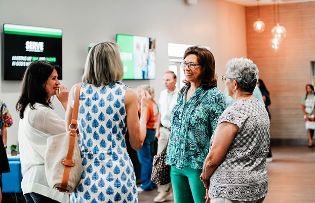 women are talking in a group in the Winter Garden campus lobby